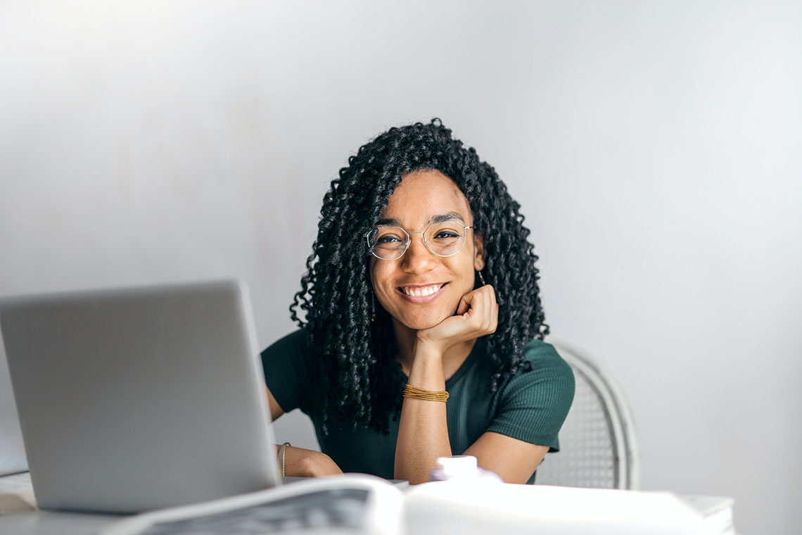 A happy businesswoman in a green shirt searches for collection agencies on a laptop computer