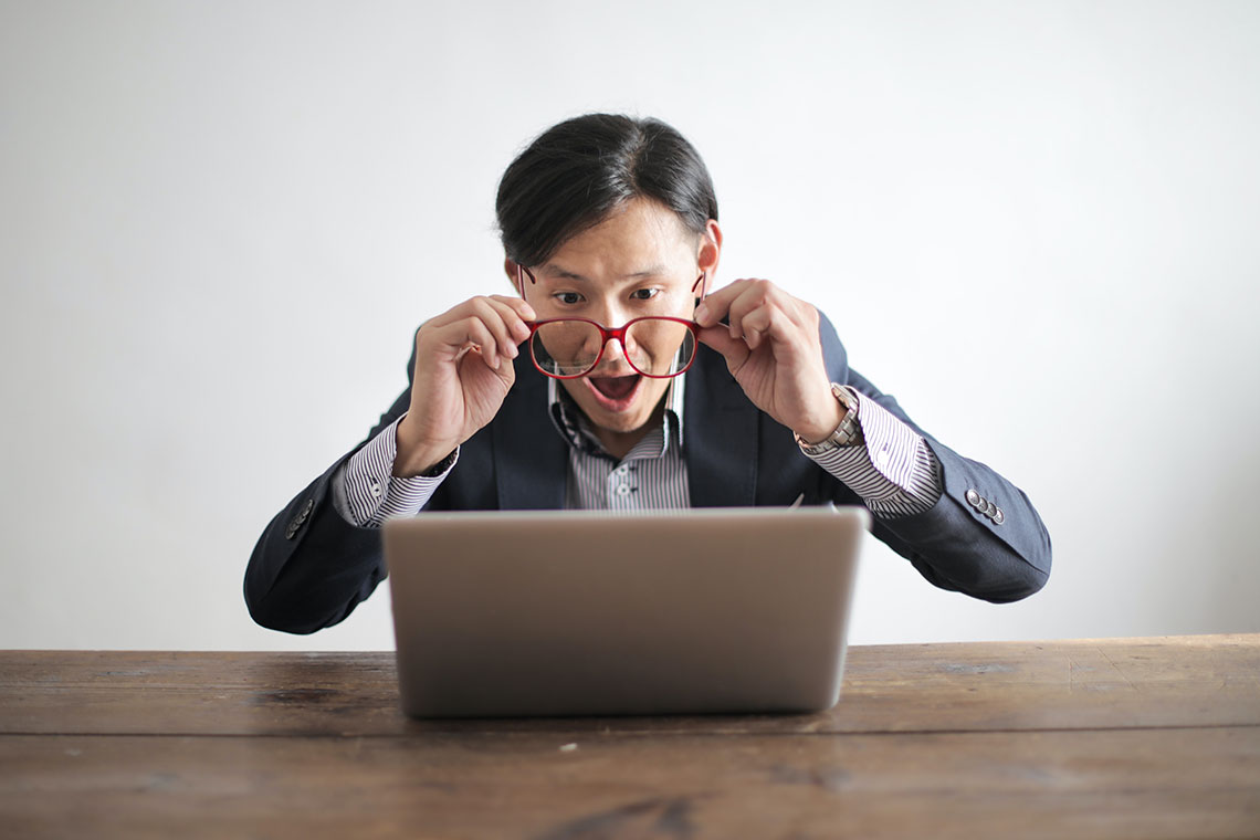 man in a suit, angrily screaming at a laptop screen
