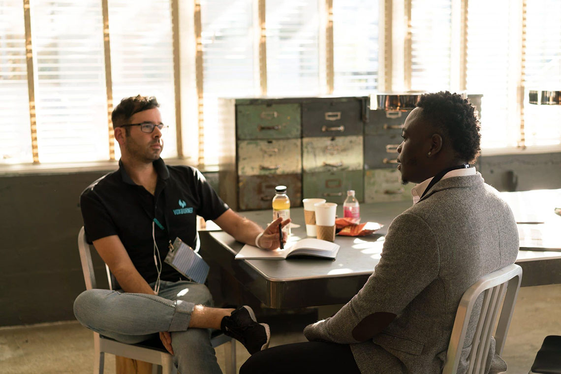 two men in a professional setting, sitting down