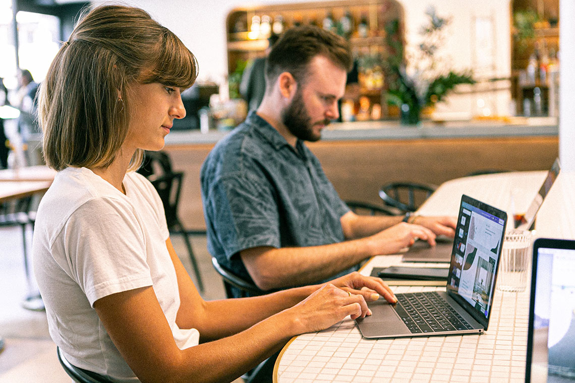 woman and man at laptops in a coffee shop