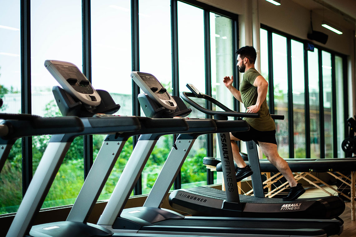 man on a treadmill amid a bunch of empty ones in front of a window