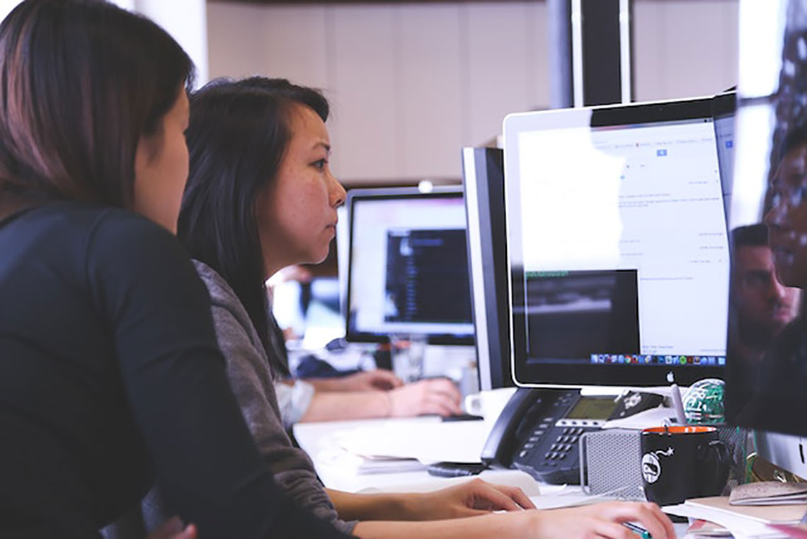 women sitting around computer screens