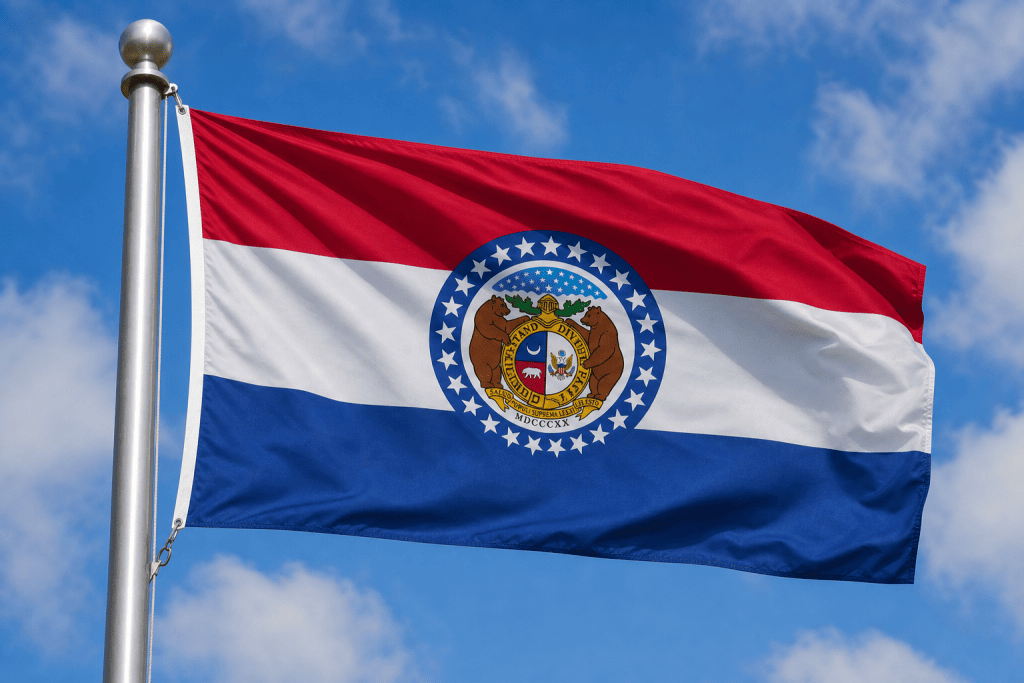 Missouri state flag waving on a flagpole against a blue sky
