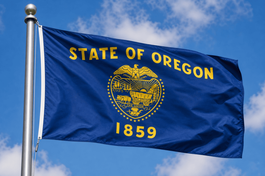 Oregon state flag waving on a flagpole against a blue sky