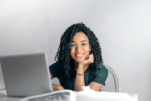 A happy businesswoman in a green shirt searches for collection agencies on a laptop computer