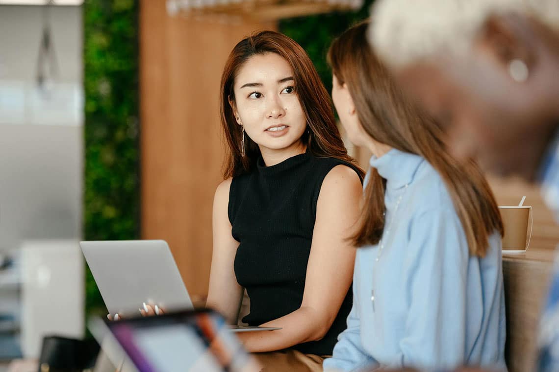 Professional woman in boardroom looks at colleague nervously