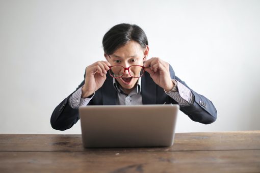 man in a suit, angrily screaming at a laptop screen