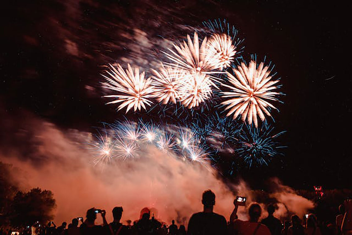 person in silhouette outside at night amid fireworks