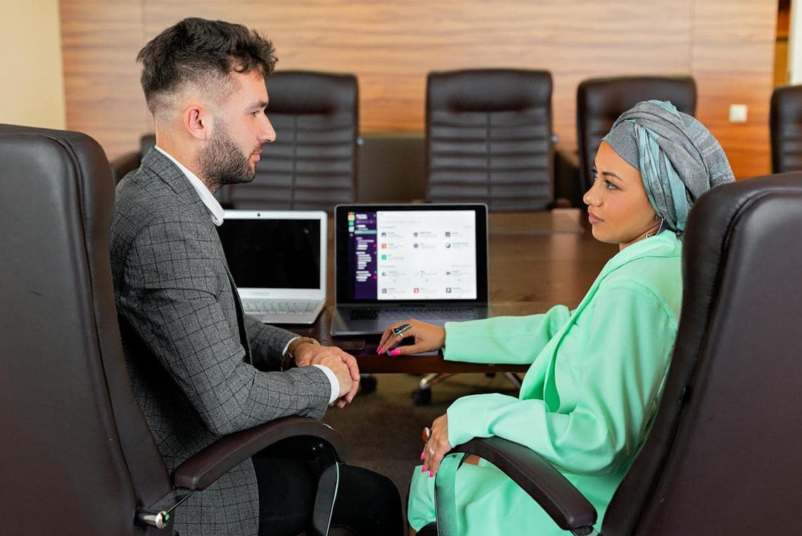professional man and woman with Slack on a laptop in the background