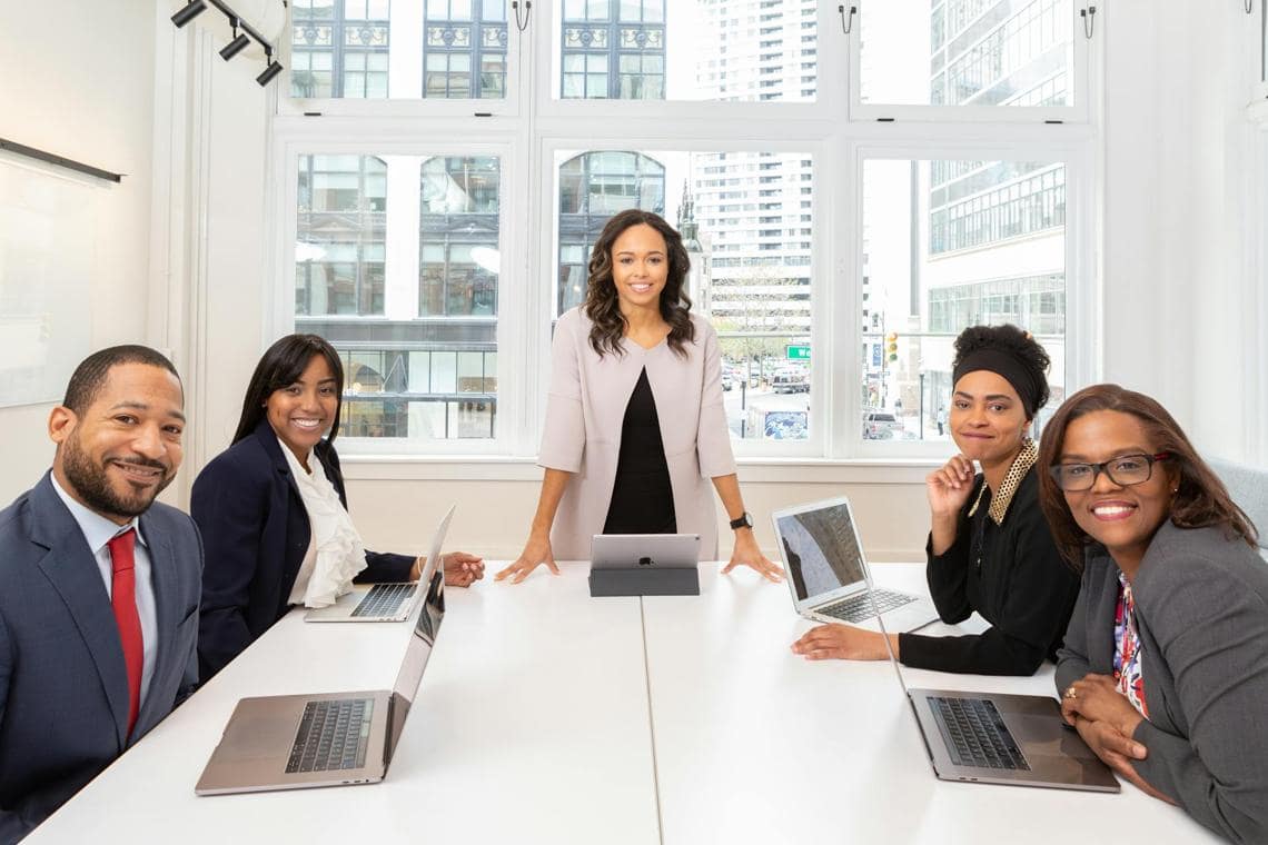small board meeting, 5 professionals looking at the camera